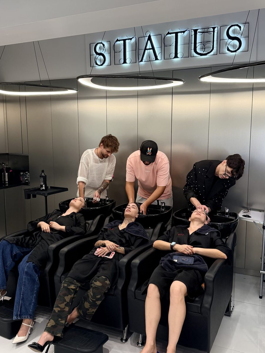 Three Status Hair Studio stylists at the backwash under the STATUS sign