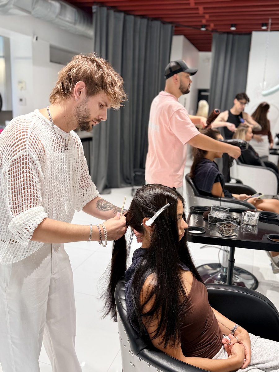 A Status Hair Studio stylist sectioning a client’s hair at the chair